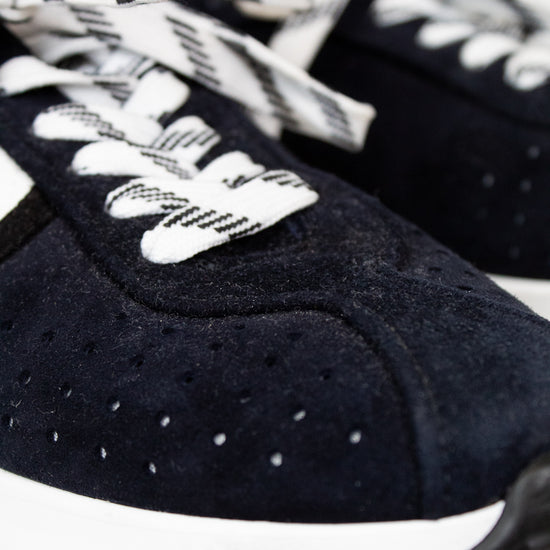Navy blue sneakers with white laces on a light background
