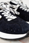 Navy blue sneakers with white laces on a light background