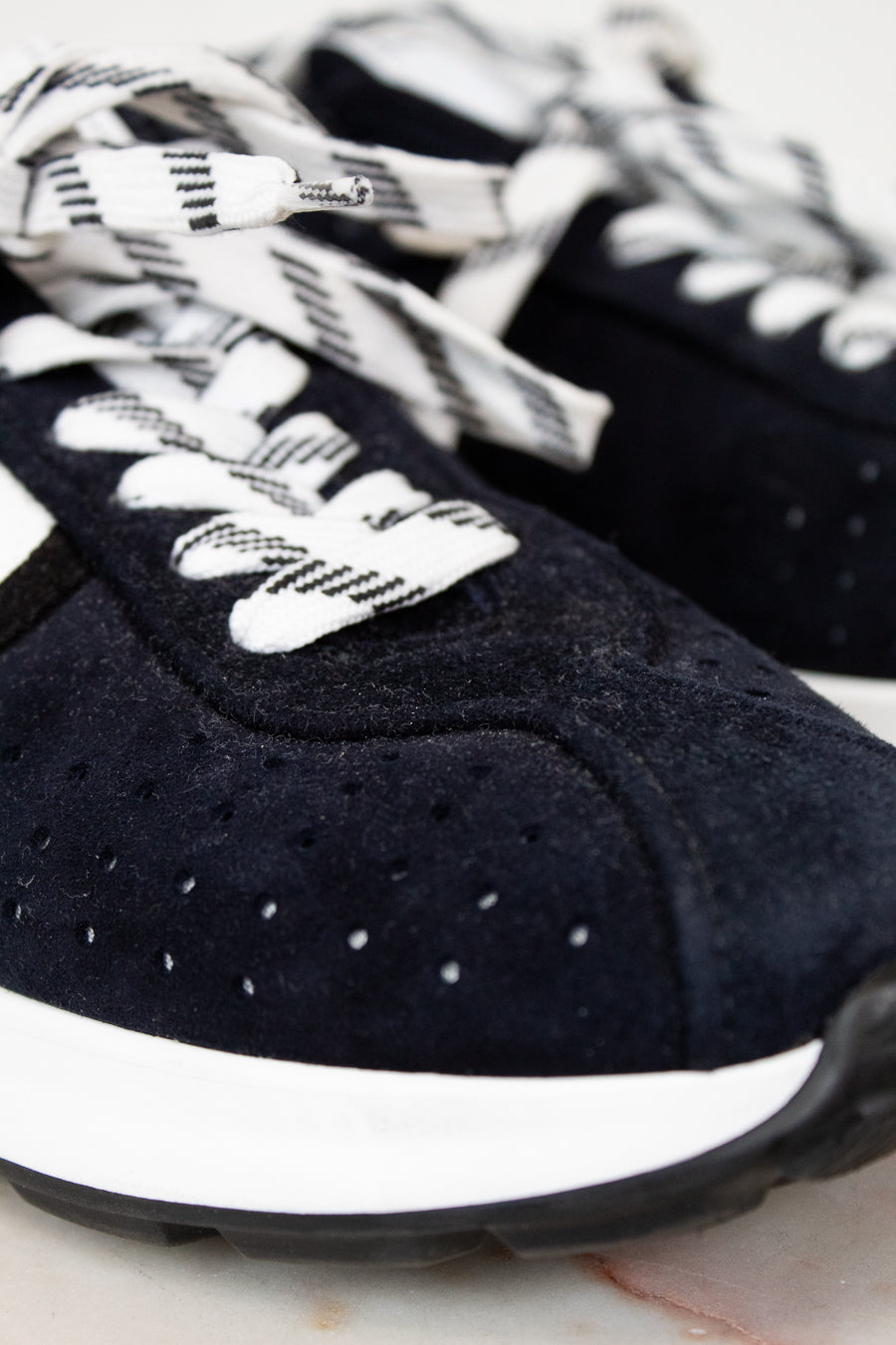 Navy blue sneakers with white laces on a light background