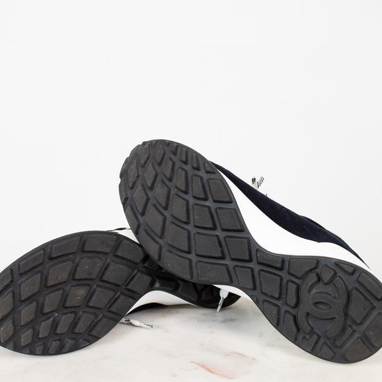 Pair of Chanel navy blue sneakers with white laces on a light gray background