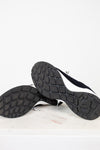 Pair of Chanel navy blue sneakers with white laces on a light gray background