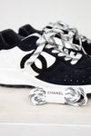 Pair of Chanel navy blue sneakers with white laces on a light gray background