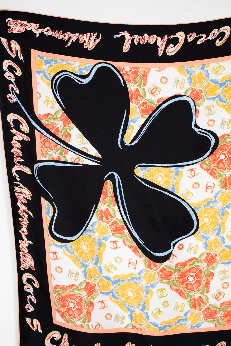 Colorful floral patterned fabric with a black clover design and 'Chanel' branding.