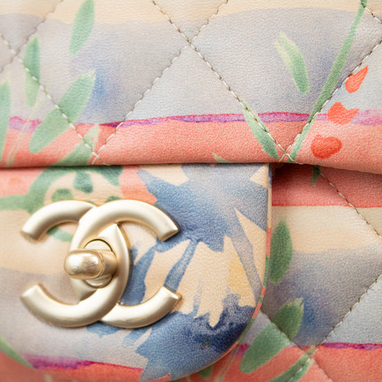Close-up of a Chanel handbag with floral pattern and gold logo.