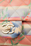 Close-up of a Chanel handbag with floral pattern and gold logo.