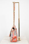 Side view of floral patterned handbag with a gold chain strap on a white background