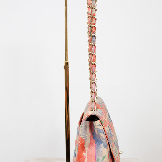 Side view of floral-patterned handbag with a chain strap on a white background