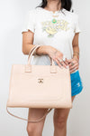 Person holding a beige handbag with a white background