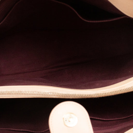 Close-up of a beige handbag with a dark interior lining.