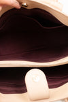 Close-up of a beige handbag with a dark interior lining.