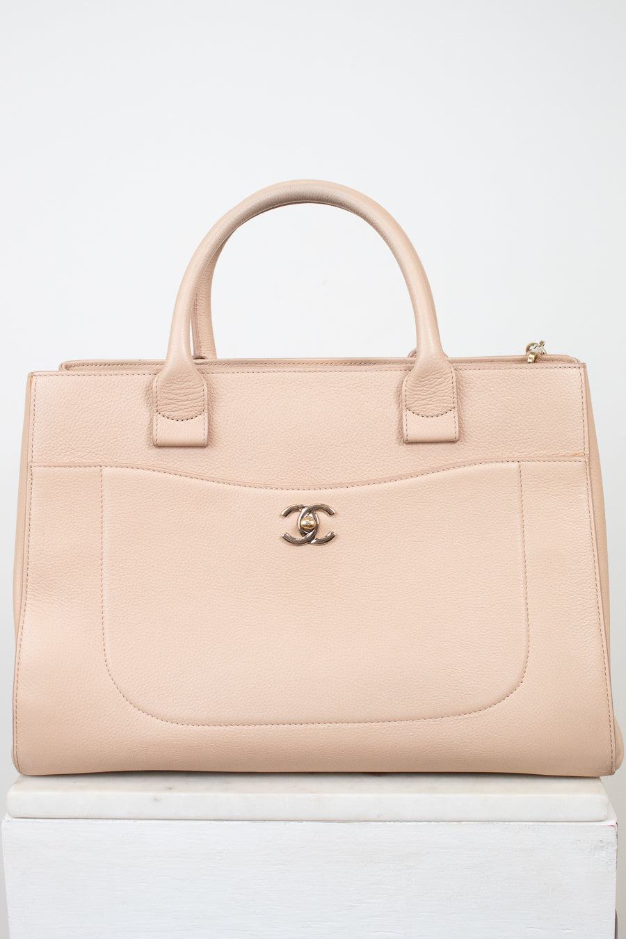 Beige handbag with Chanel logo on a white background