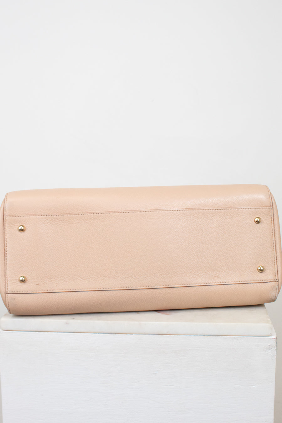Beige handbag on a white surface with a white background
