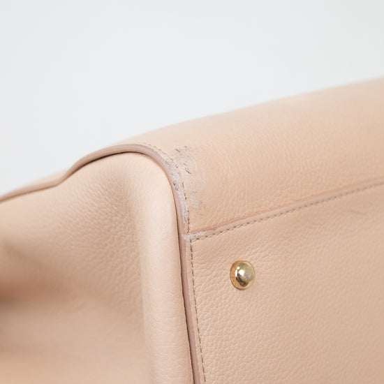 Close-up of a beige leather bag with gold hardware on a light gray background
