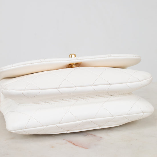 White clutch bag with gold clasp on a light gray background