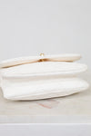 White clutch bag with gold clasp on a light gray background