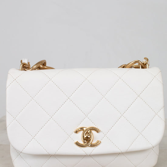 White quilted handbag with gold hardware on a light gray background