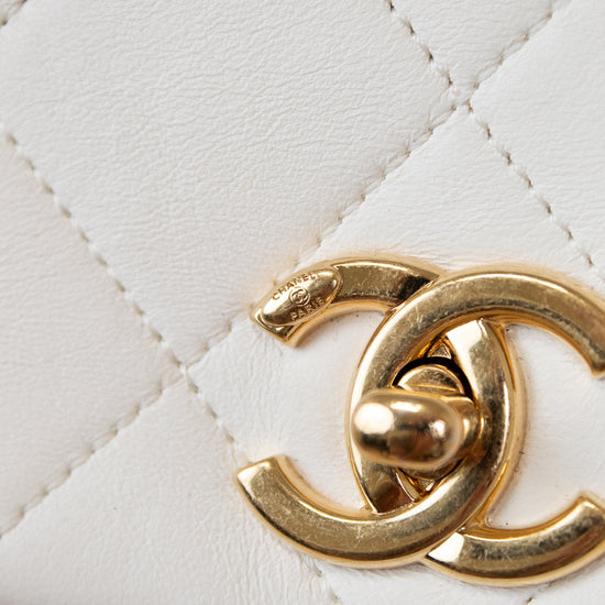 Close-up of a gold Chanel logo on a white quilted leather background