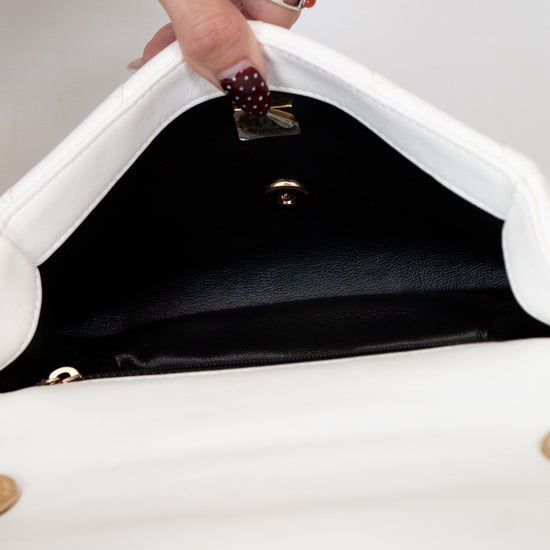 Close-up of a hand opening a white handbag with a black interior.