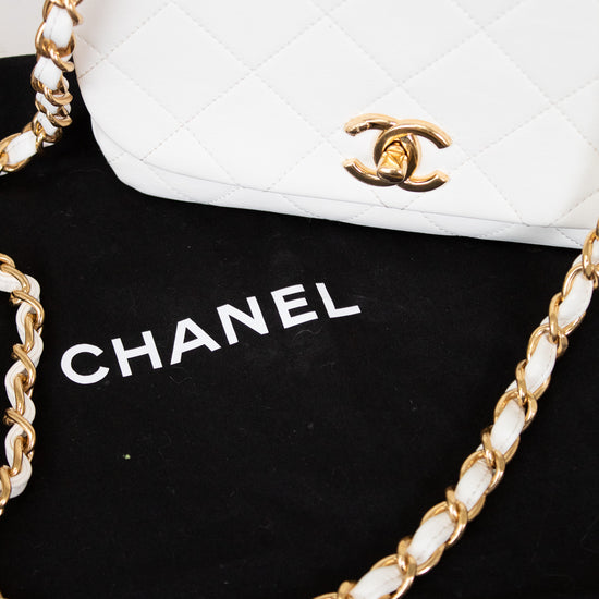 White Chanel handbag with gold chain on a black background
