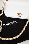 White Chanel handbag with gold chain on a black background