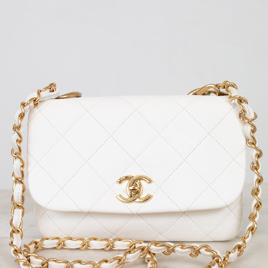 White quilted handbag with gold chain strap on a light gray background