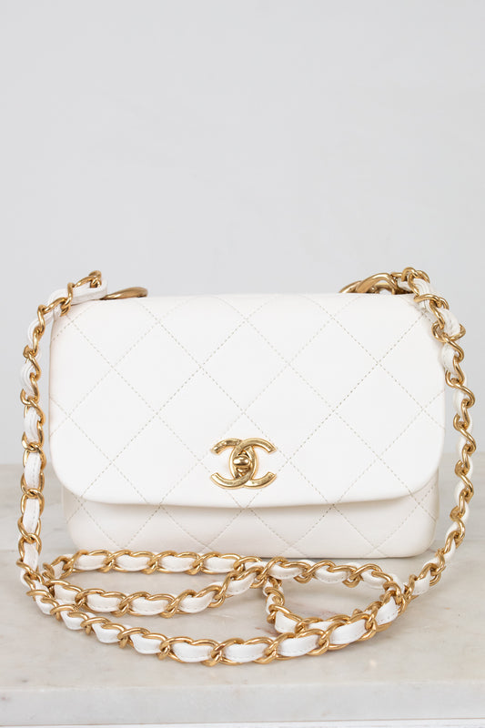White quilted handbag with gold chain strap on a light gray background
