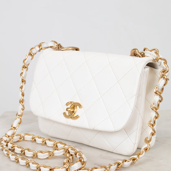 White handbag with gold chain and logo on a white background