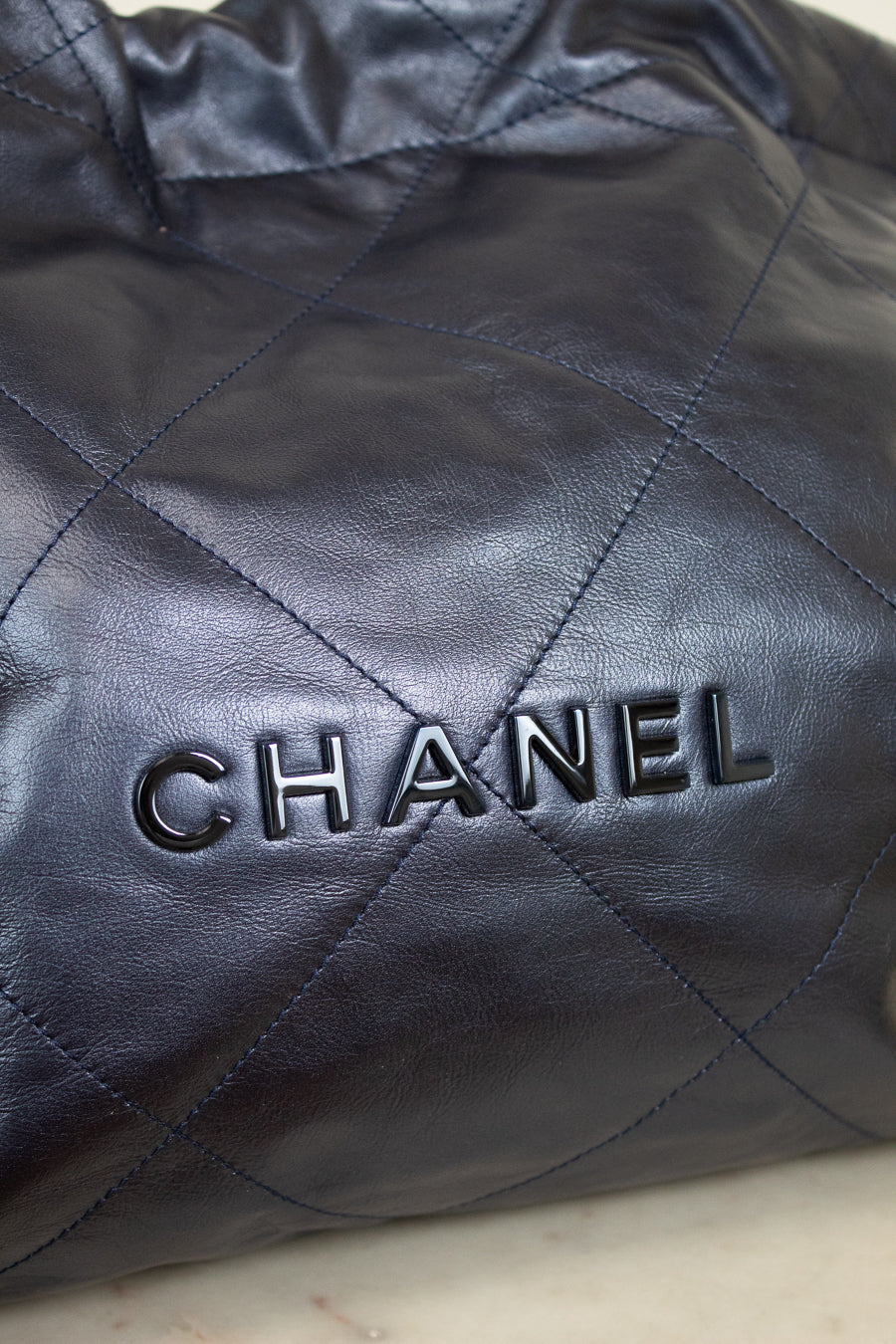 Close-up of a quilted navy leather Chanel handbag.