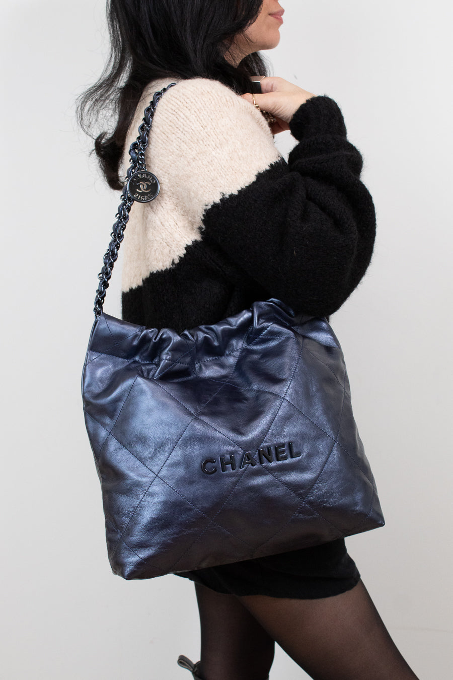 Person holding a Chanel handbag against a plain background