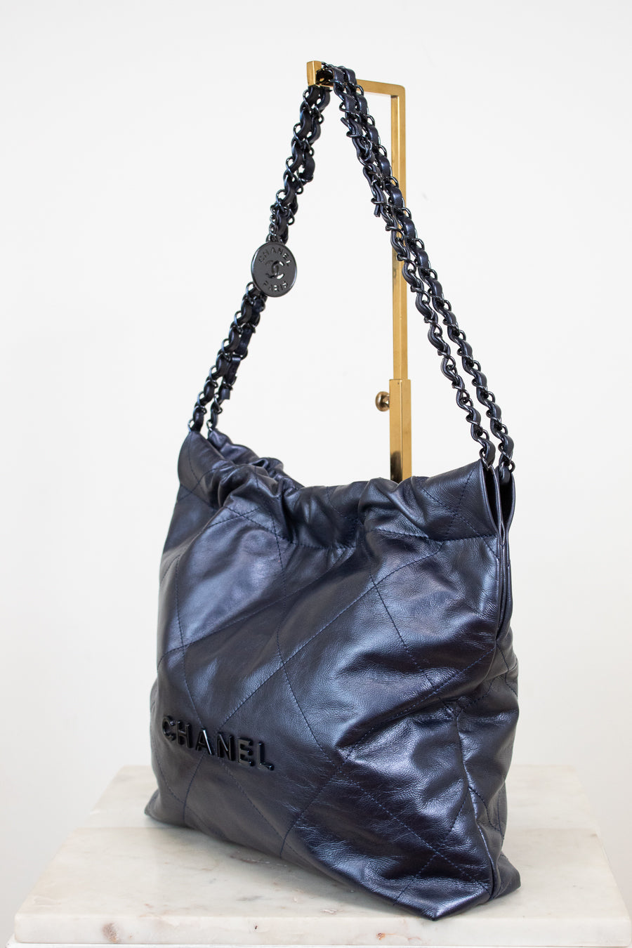 Chanel navy handbag with chain detail on a white background
