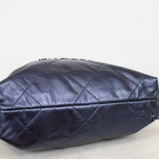 Navy quilted handbag on a light marble surface with a white background