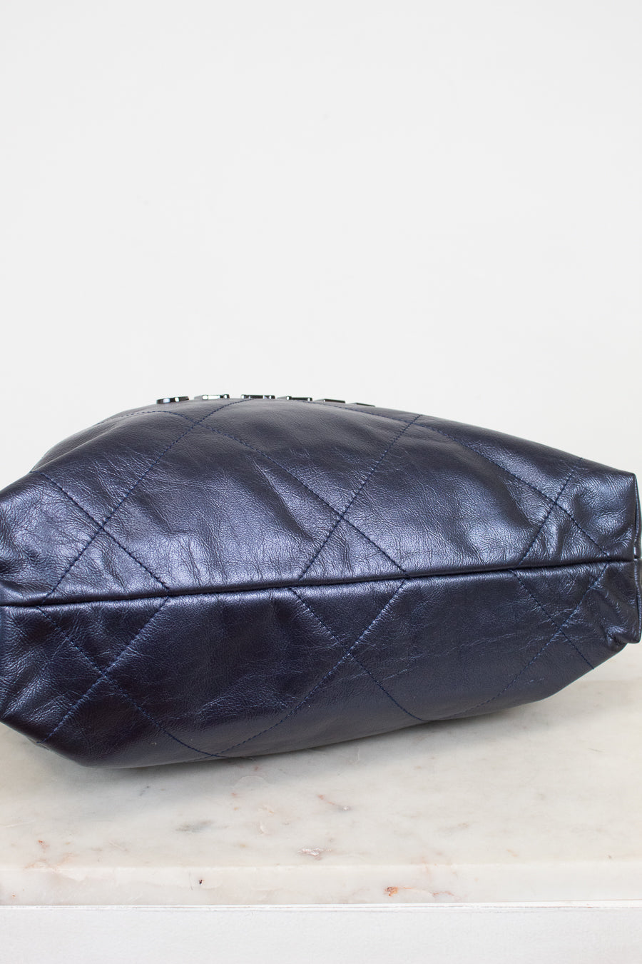 Navy quilted handbag on a light marble surface with a white background