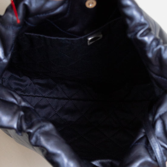 Close-up of interior of navy quilted handbag with a person's hand holding it.