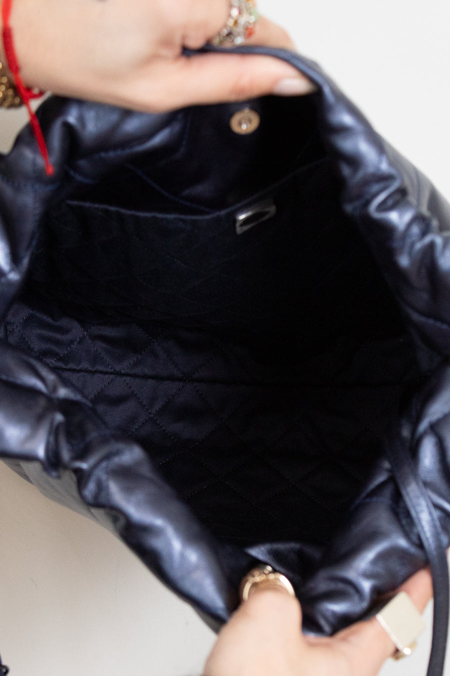 Close-up of interior of navy quilted handbag with a person's hand holding it.