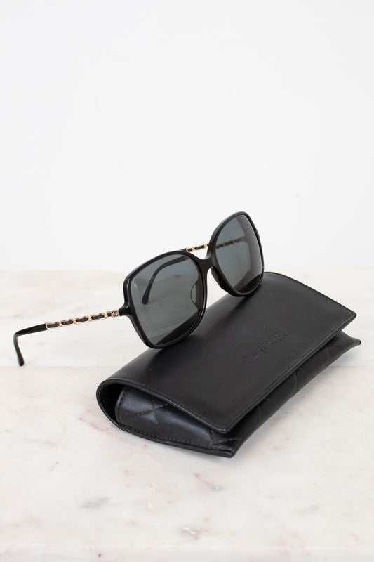 Black sunglasses on a black leather case against a white background
