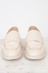 A pair of cream-colored leather loafers with decorative braided detailing on the sides, displayed on a light marble surface against a white background.
