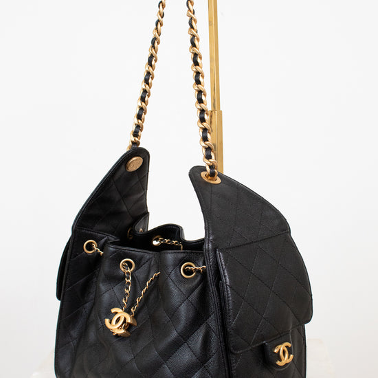 Black quilted handbag with gold chain strap on a white background