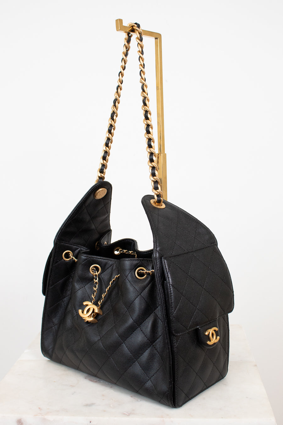 Black quilted handbag with gold chain strap on a white background
