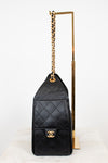 Black quilted handbag with gold chain and clasp on a white background