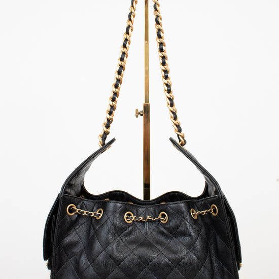 Black quilted handbag with gold strap details on a white background 