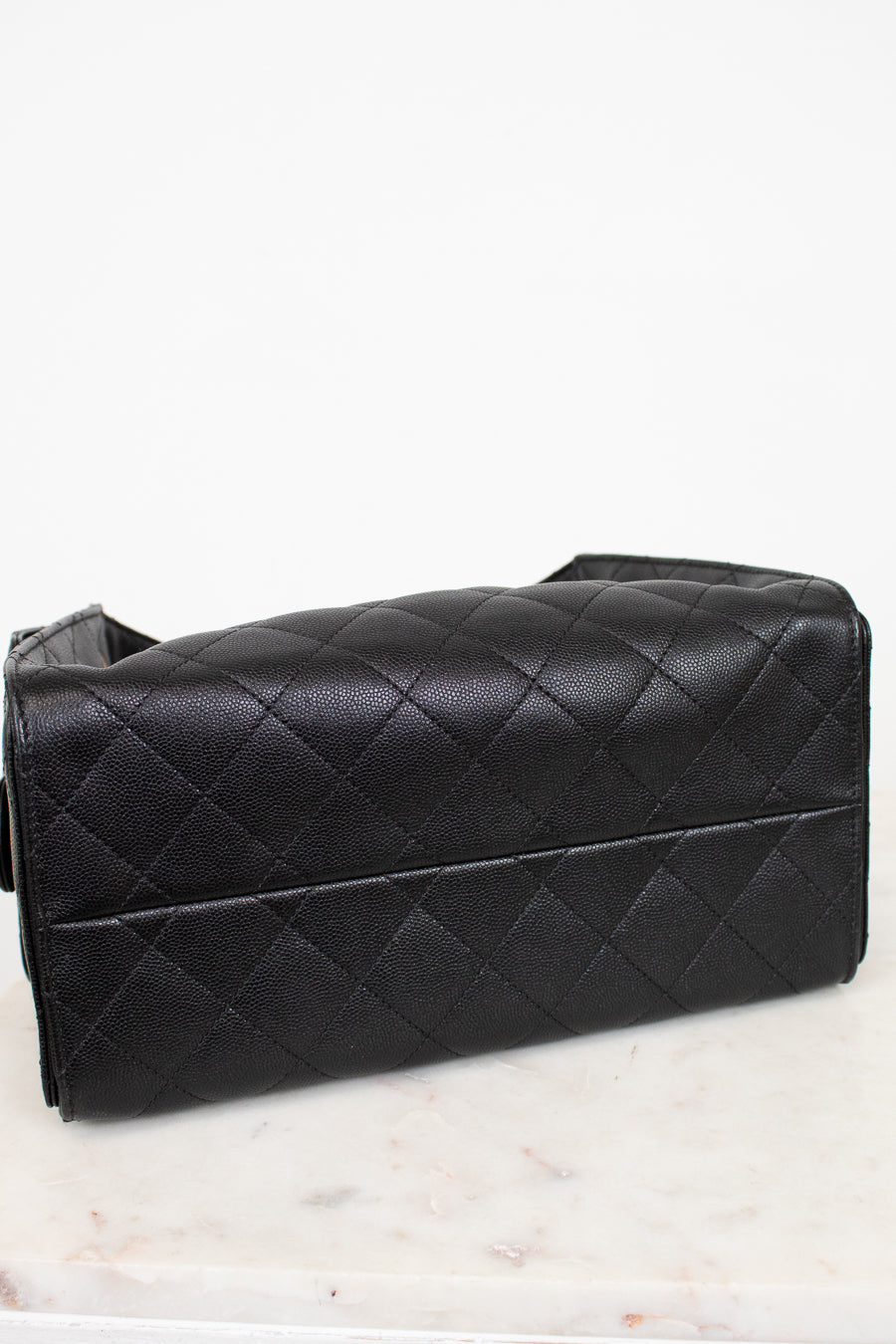 Black quilted handbag on a white marble surface