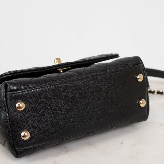 Black handbag with gold accents on a light gray background