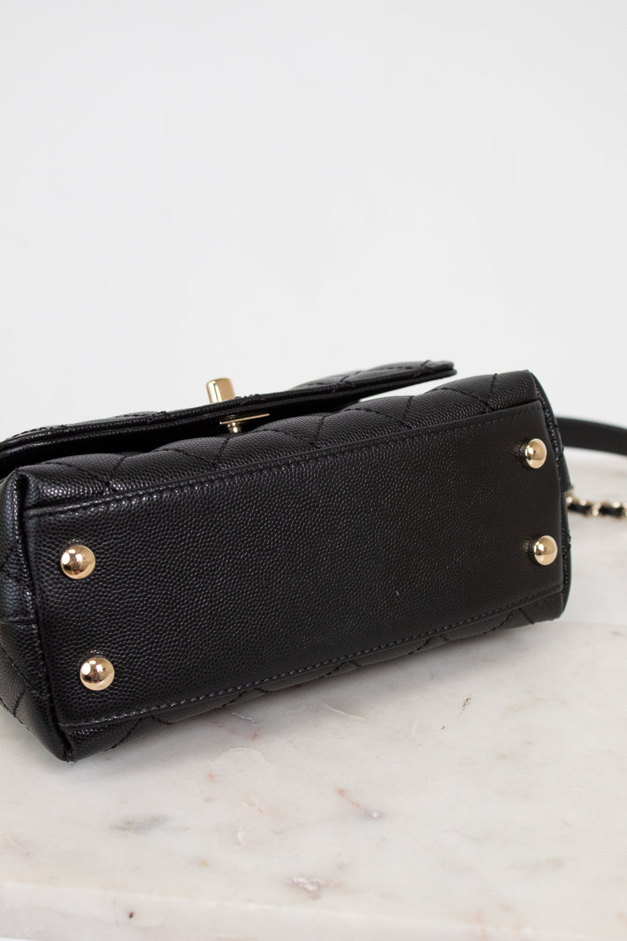 Black handbag with gold accents on a light gray background