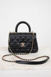 Black quilted handbag with gold chain on a white background