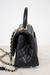 Black quilted handbag with a chain detail on a white background