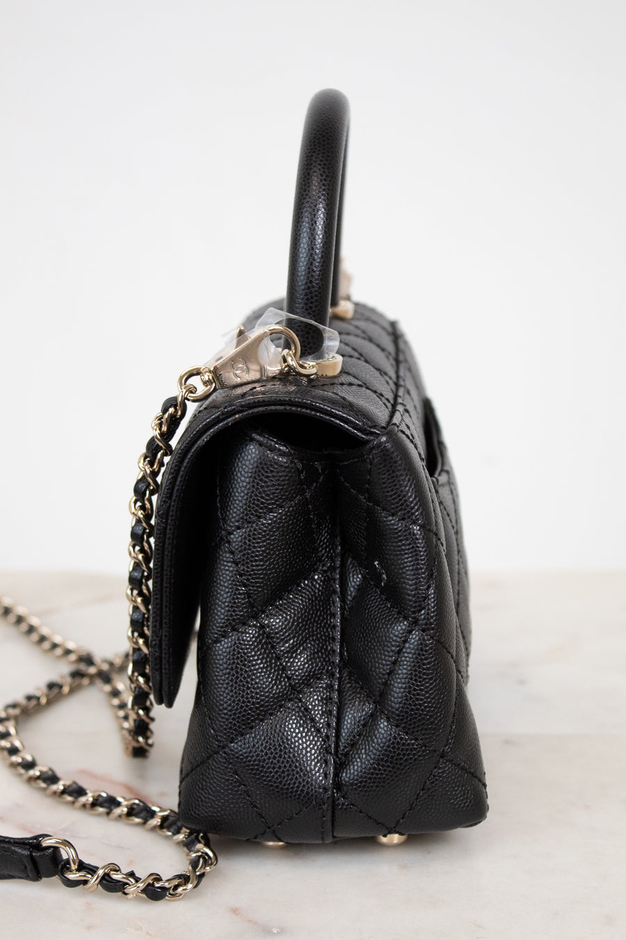 Black quilted handbag with a chain detail on a white background