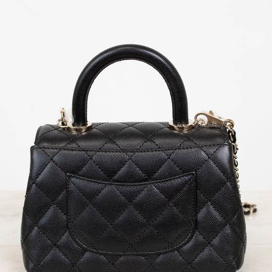 Black leather handbag with gold hardware and chain detail on a white background