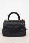 Black leather handbag with gold hardware and chain detail on a white background