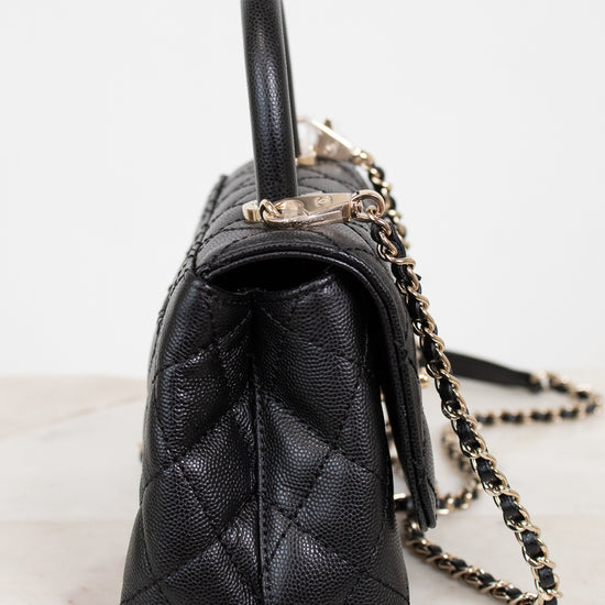 Black quilted handbag with a chain strap on a light background