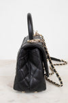 Black quilted handbag with a chain strap on a light background